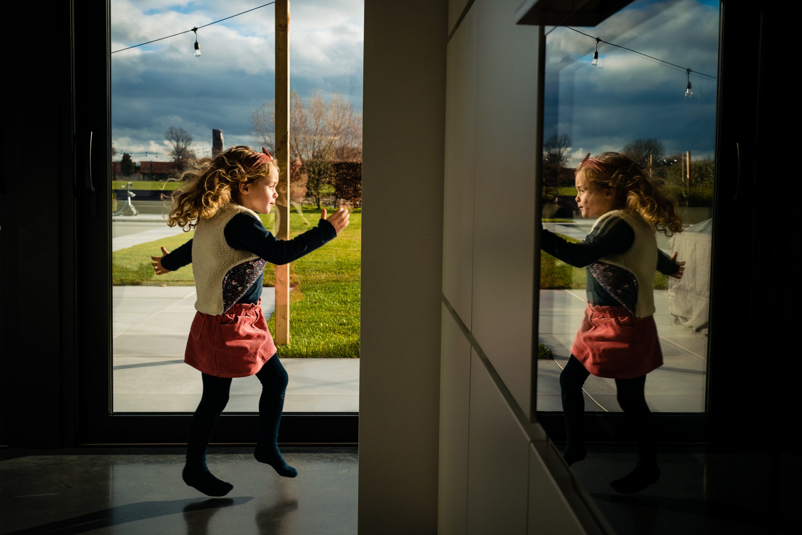 reflet d'une petite fille sautillant dans la cuisine lors d'un reportage photo famille à Gand