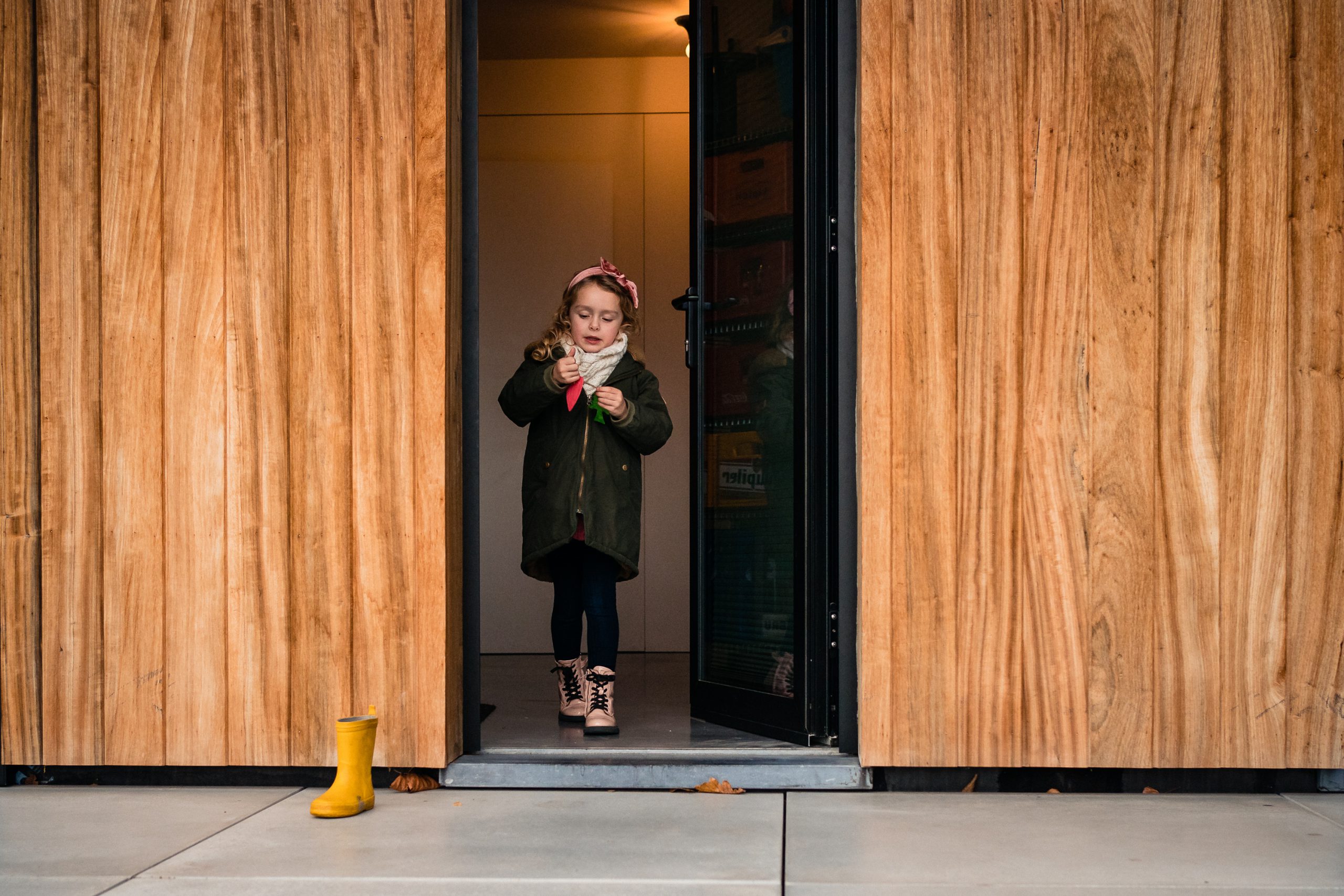 Petite fille dans l'encadrement de porte pour jouer dehors lors d'un reportage photo famille à Gand