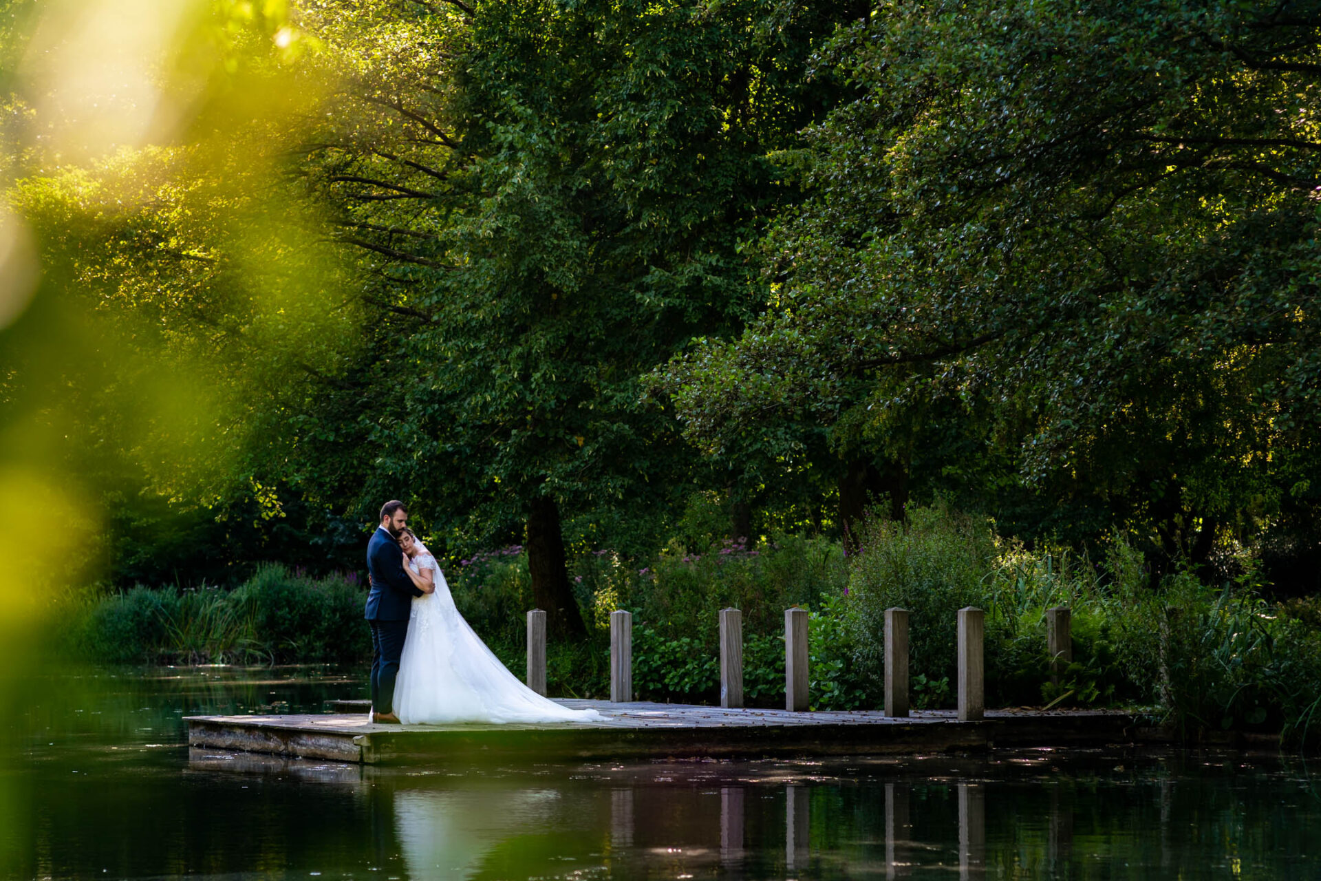 Les mariés s'enlacent sur un ponton au bord de l'étang du Domaine de Beronsart pendant le golden hour