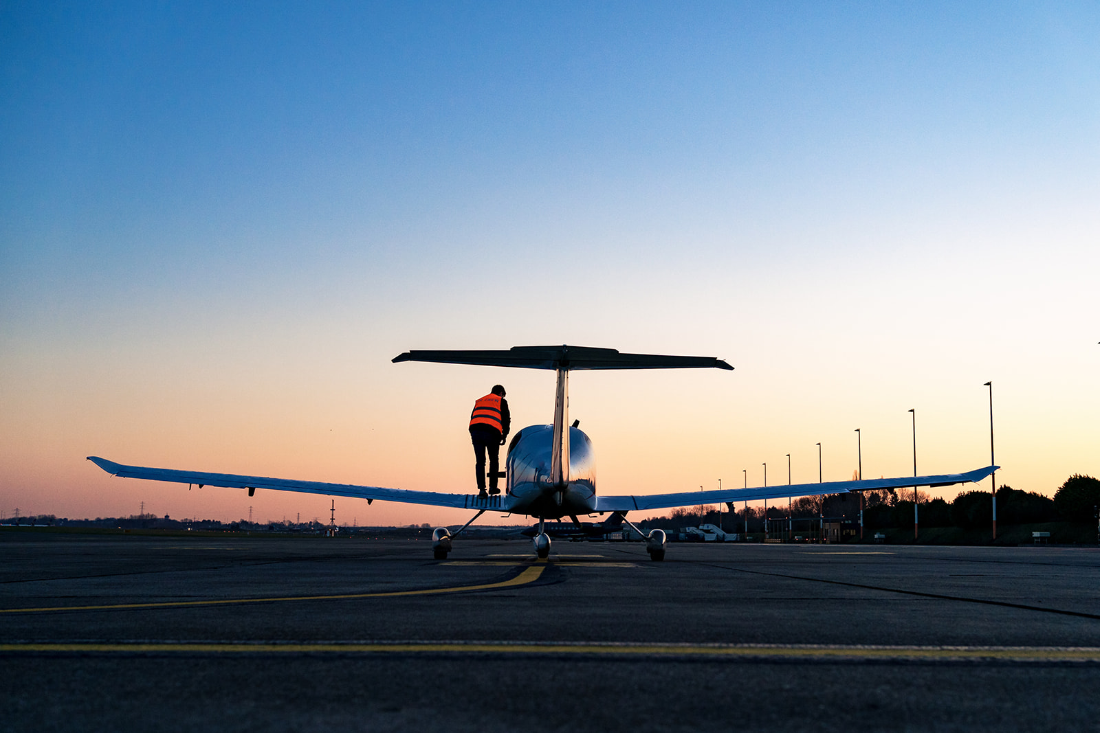 Silhouette du pilote montant dans son avion à l'aéroport de Charleroi lors du lever du soleil
