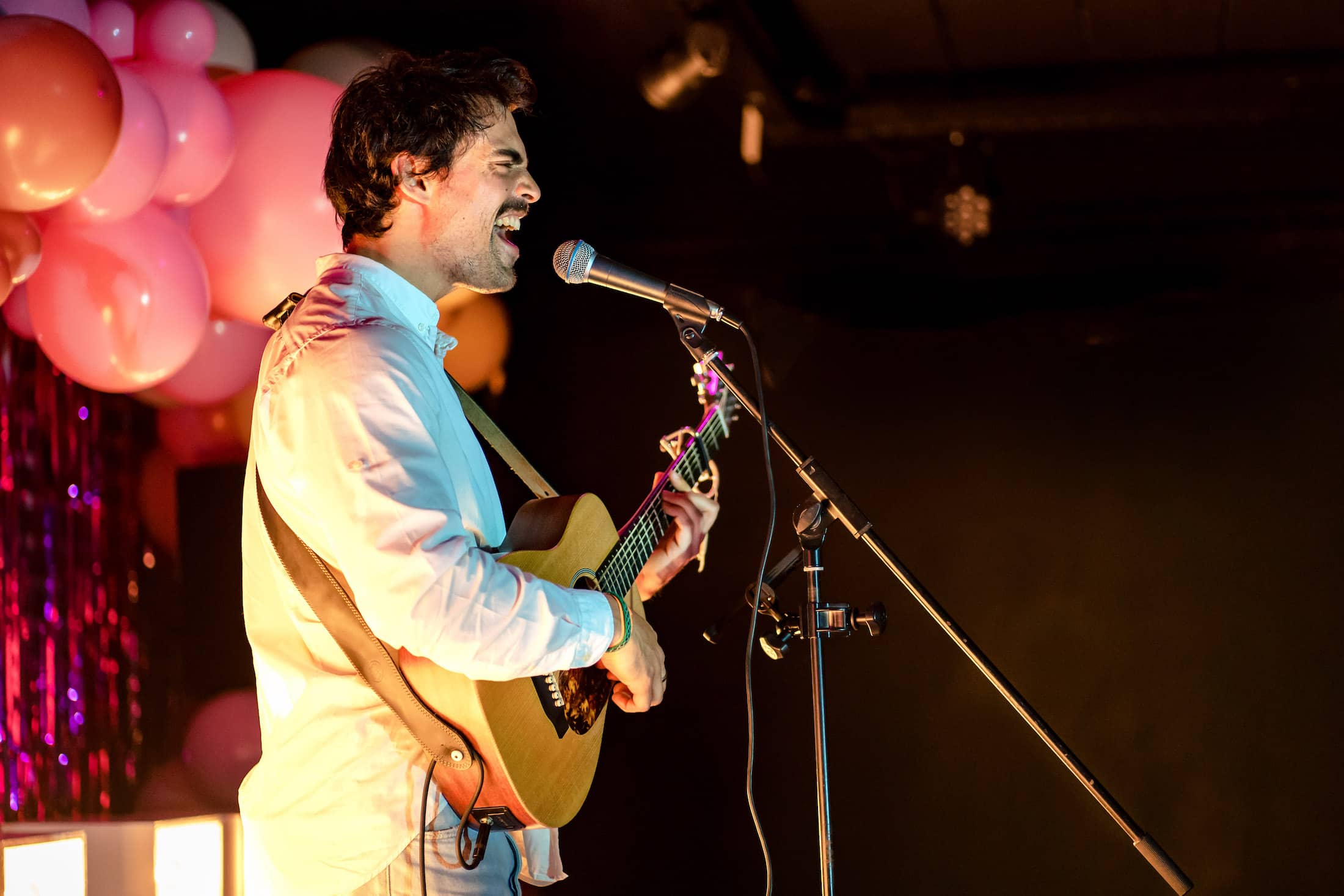 Le chanteur Livio Hans chante avec sa guitare lors de la soirée annuelle de l'association Bewe  au Citizen Kane à Louvaila-Neuve.