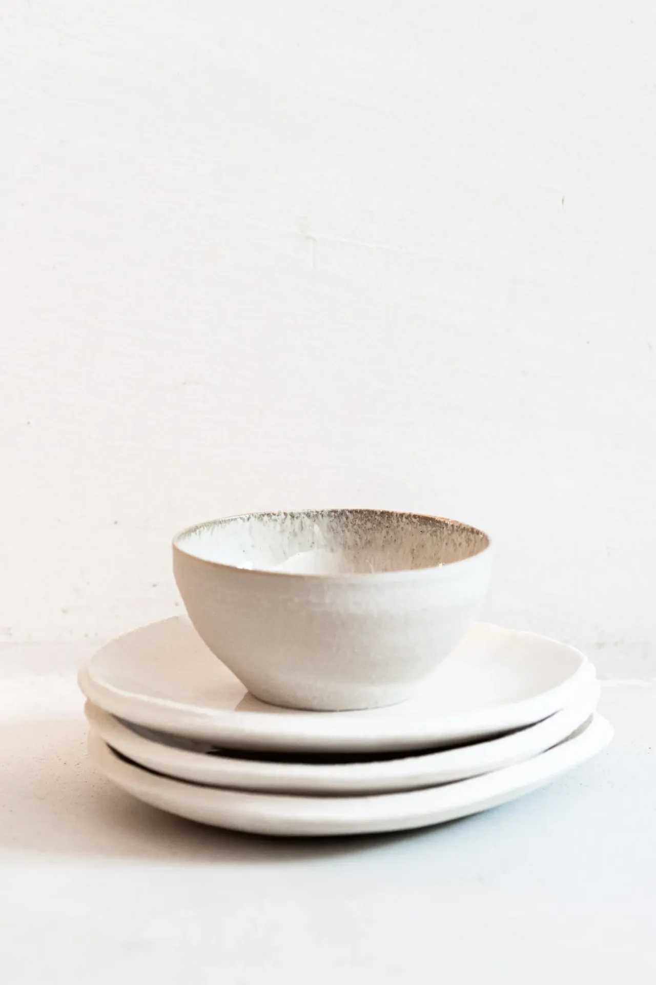 Trois assiettes et un bol épilé en céramique blanc sur fond blanc