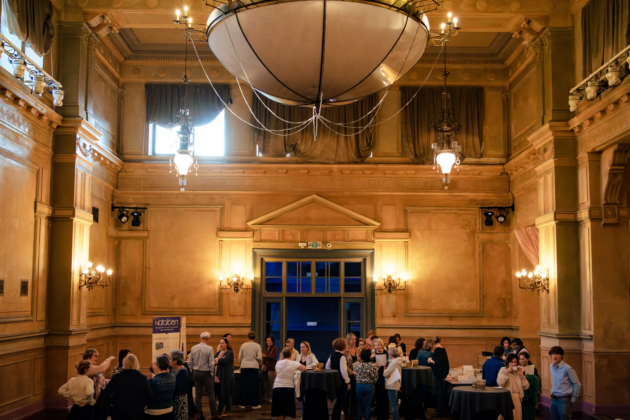 Une dizaine de personnes attendent dans une salle de reception le début d'une conférence au Palais de Plume à Ittre