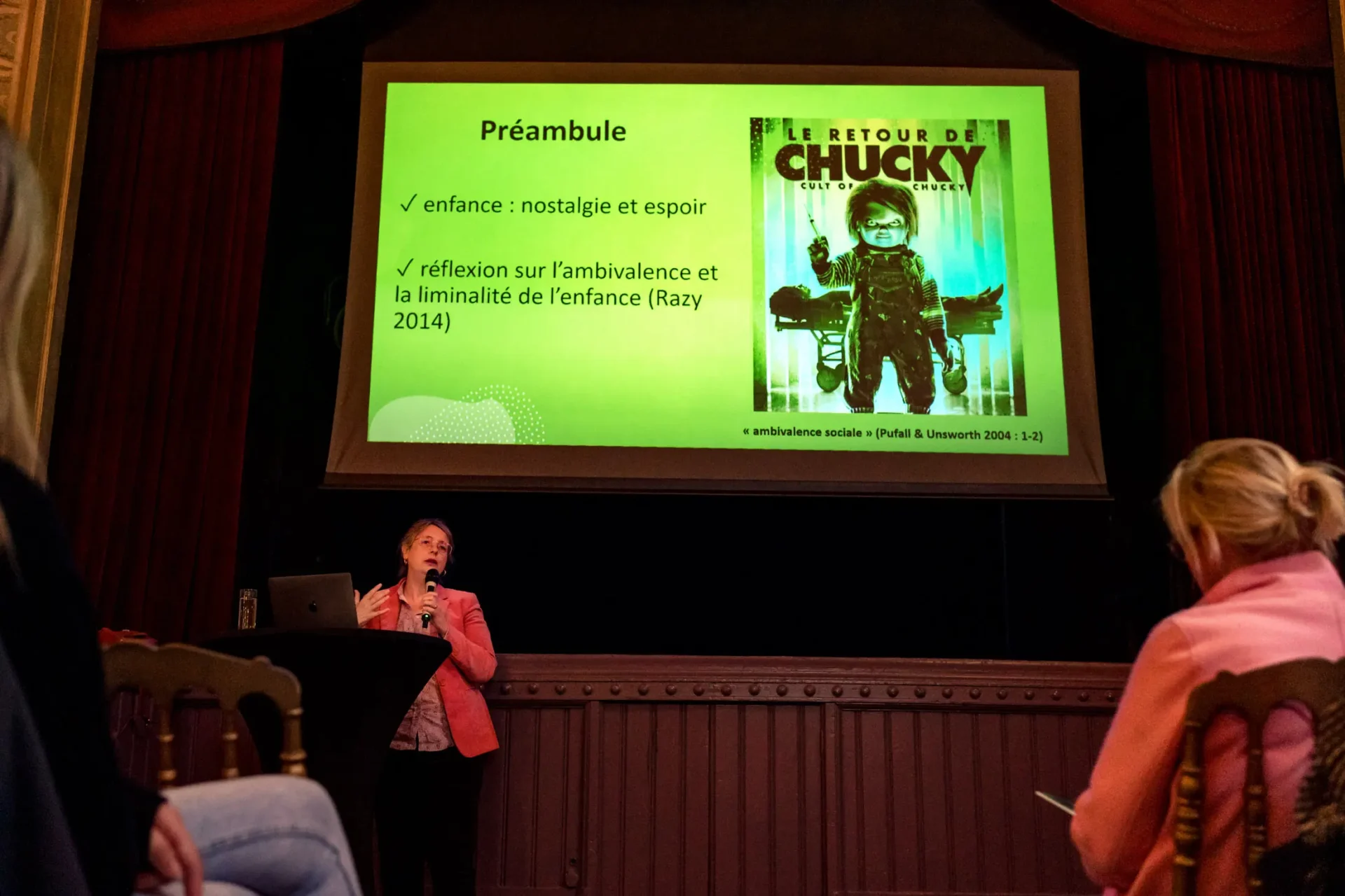 Une oratrice présente une conférence avec une image de Chucky sur la toile