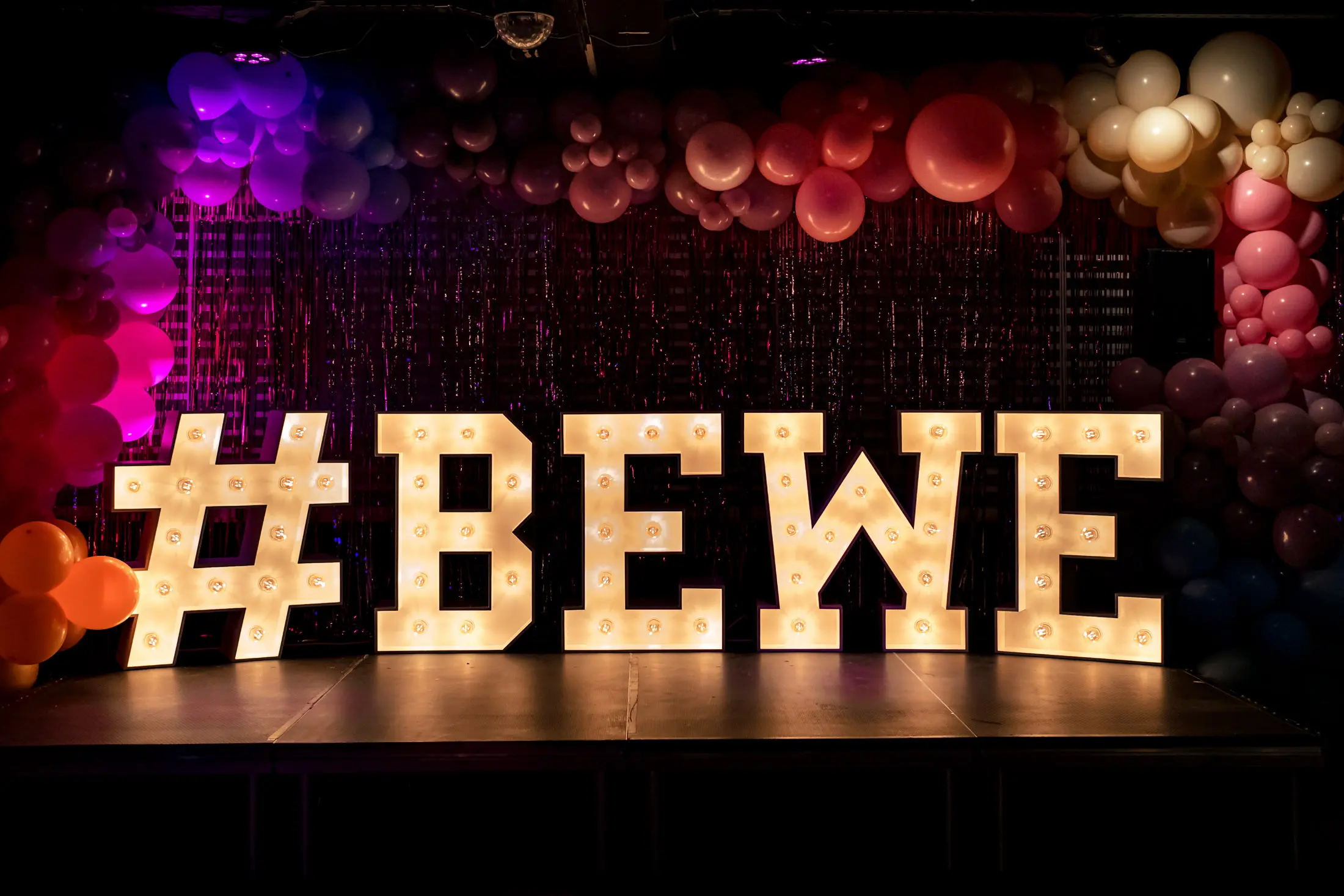 Lettre lumineuse sur podium décrivant #BEWE lors d'un événement Brabant Wallon