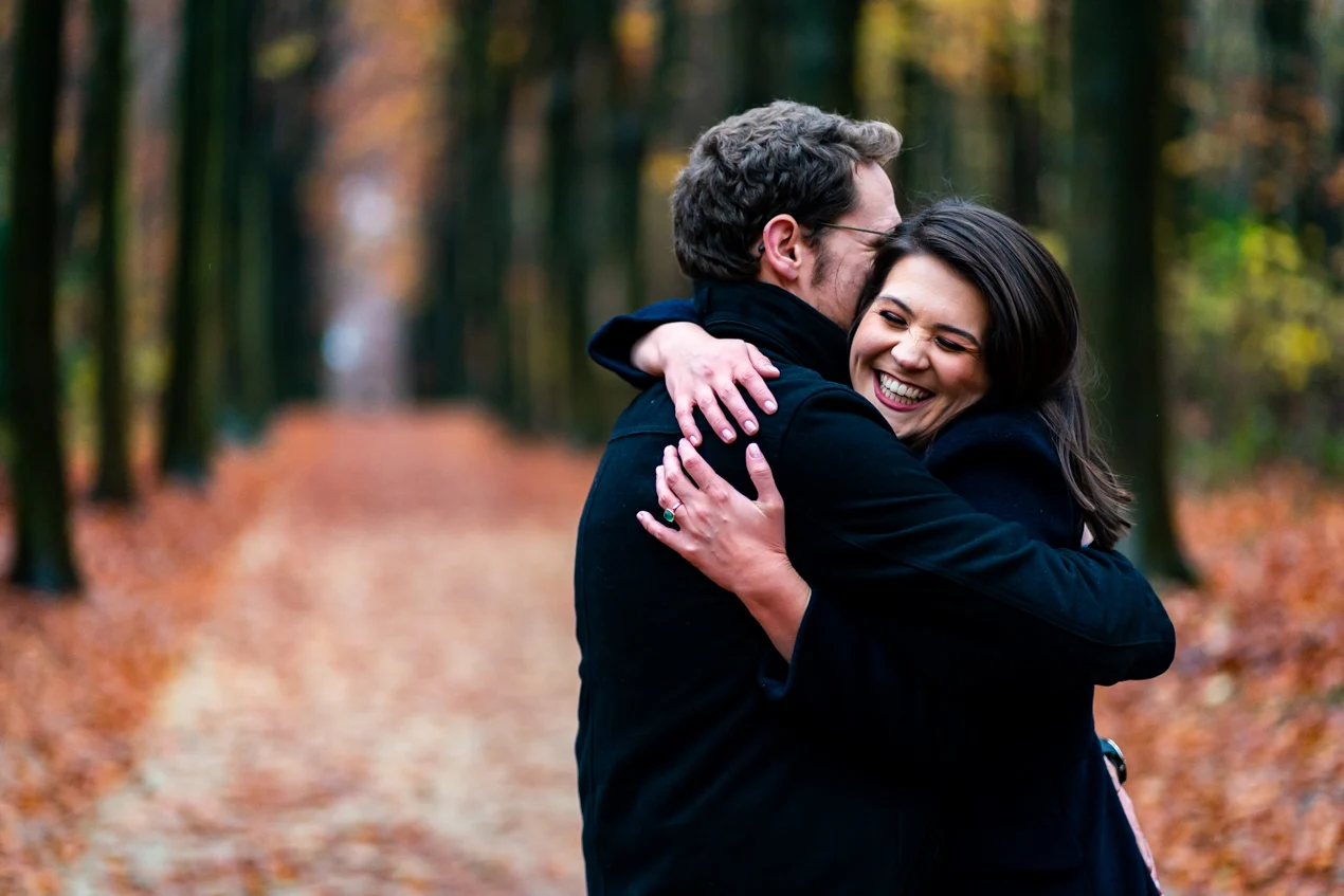 Une femme dans les bras d'un homme sur un chemin dans le bois de la Cambre à Bruxelles avec des belles couleurs d'automne 