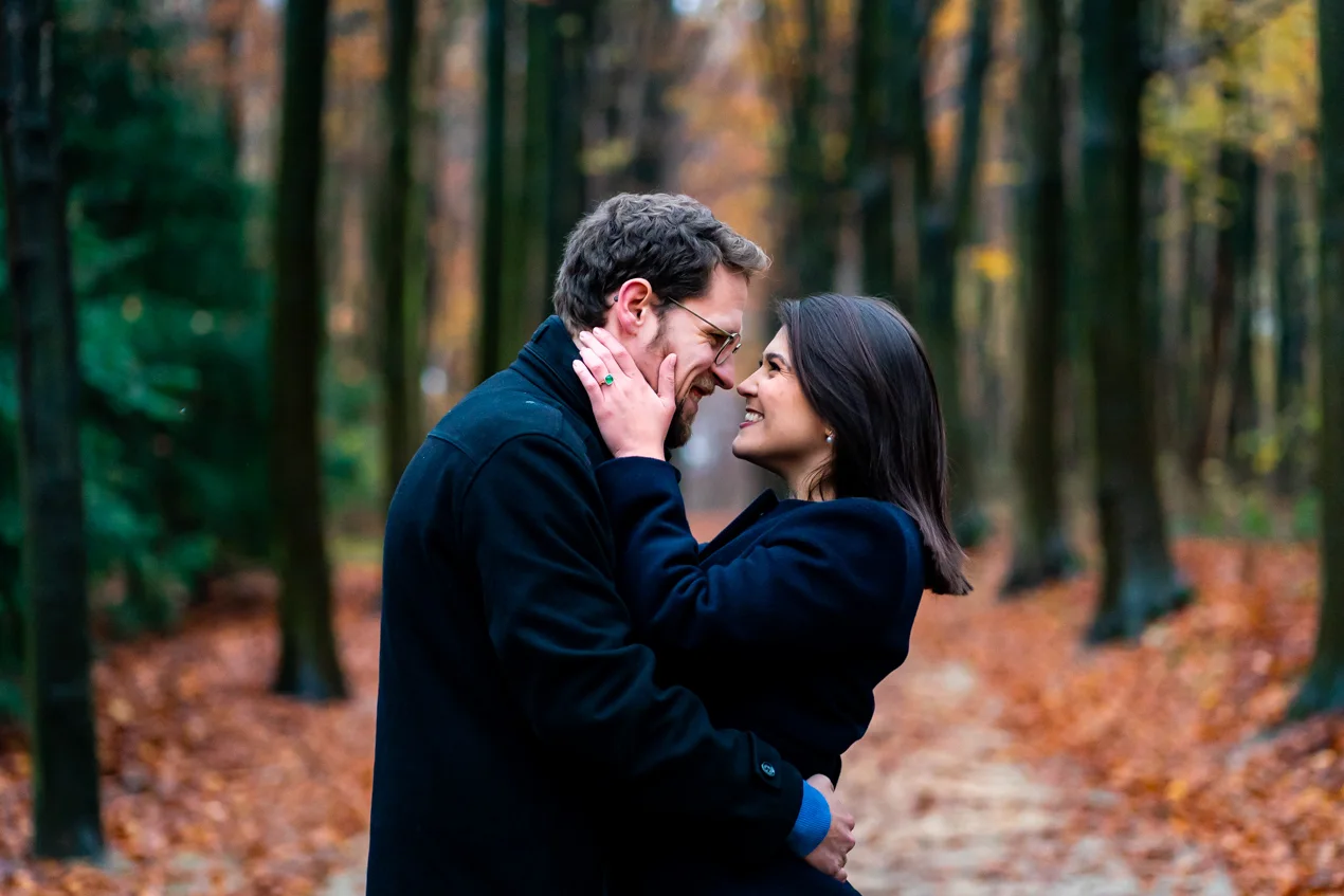 Une femme tenant le visage d'un homme sur chemin dans le bois de la Cambre à Bruxelles avec des belles couleurs d'automne