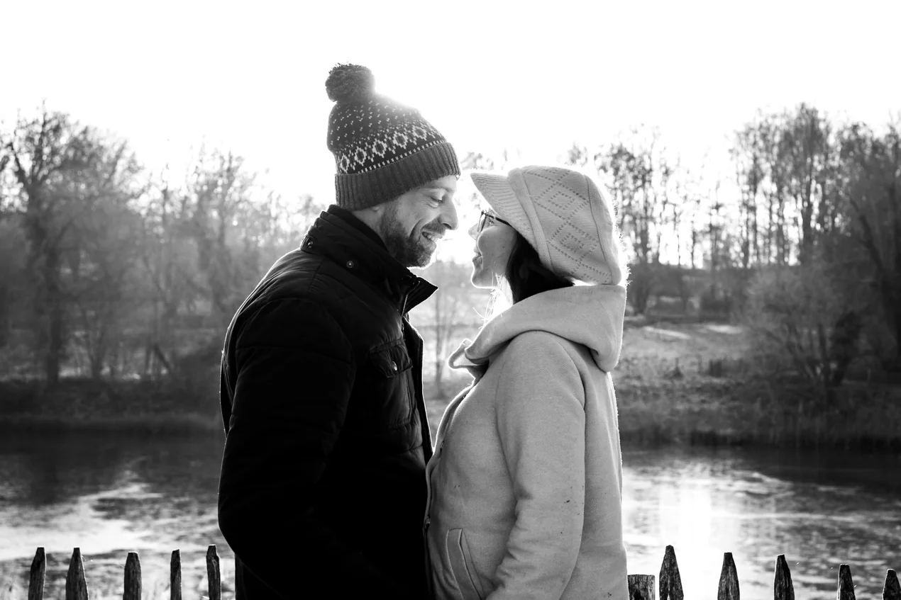 Un homme et une femme se tiennent l'un en face de l'autre à contre-jour avec l'étang du rouge cloitre en second plan à Bruxelles lors d'une session photo de couple 