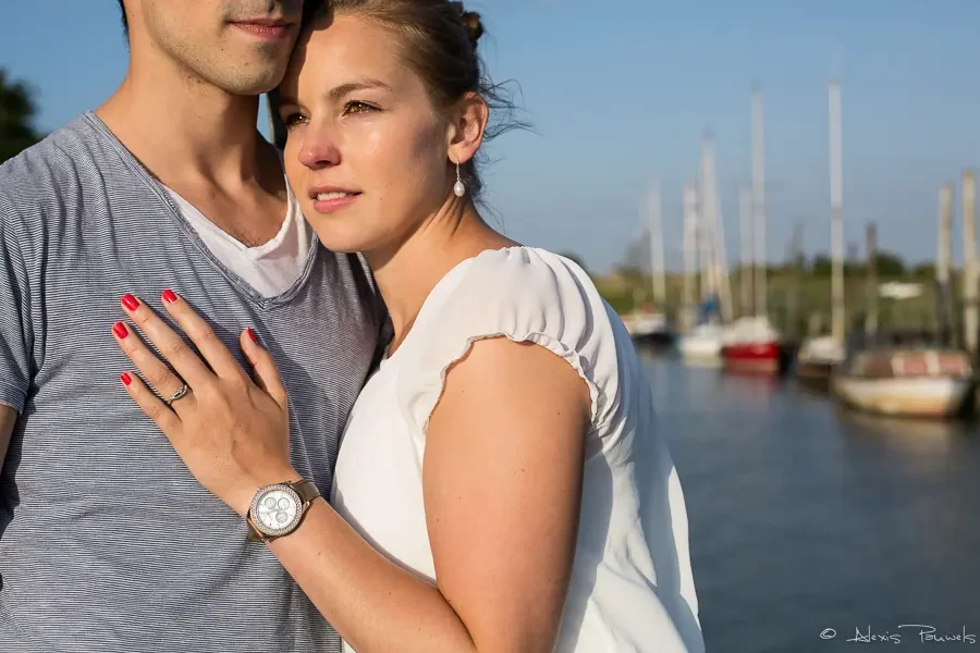 Une femme est appuyé contre le torse d'un homme au soleil couchant avec le port de plaisance de Doel en arrière plan