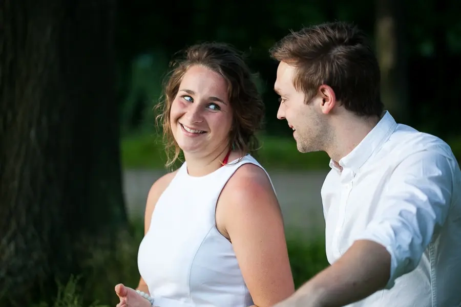 Une femme en débardeur blanc regarde amoureusement un homme en chemise blanche lors d'une séance photo de couple